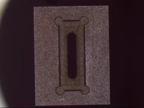Microscope image of a pick-up nozzle's tip face with a slotted vacuum opening.